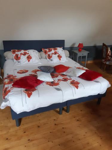 a bed with red and white blankets and pillows at Les Coquelicots in Saint-Urbain