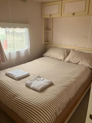 a bedroom with a bed with two towels on it at Hollie’s Hemsby holidays - static caravan in Hemsby
