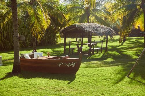 a small boat sitting on the grass near palm trees at Villas Taturé in São Miguel dos Milagres