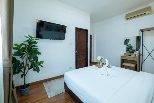 a bedroom with a white bed and a plant at April Pool Villa Airport in Chiang Mai