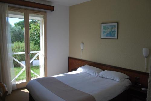 a bedroom with a bed and a large window at Hôtel Le Barry, Toulouse Nord in Gratentour
