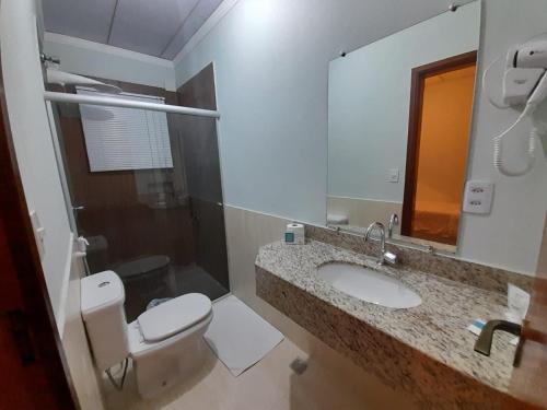 a bathroom with a toilet and a sink and a mirror at Hotel Itapema in Valinhos
