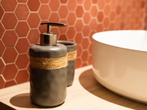 a soap dispenser sitting on a table next to a bowl at Le Saunerie - Sleep in Sisteron in Sisteron