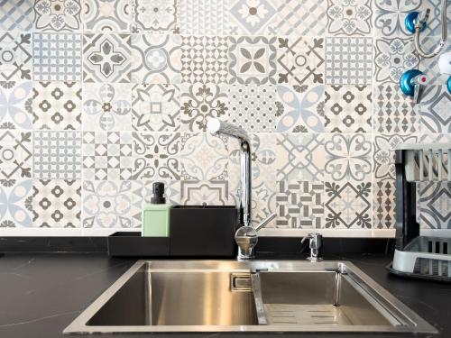 a stainless steel sink in a kitchen with a tile wall at Apartamento Mucha Vida Little Apartments in Cádiz