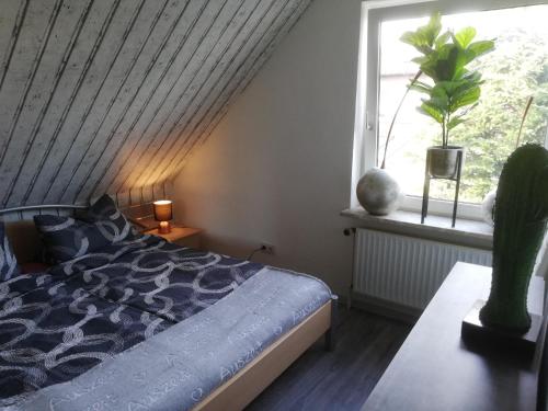 1 dormitorio con cama y ventana con cactus en Küstensonne, en Esens