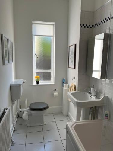 a white bathroom with a toilet and a sink at Elegant Bloomsbury Apartment in Tunbridge Wells in Royal Tunbridge Wells