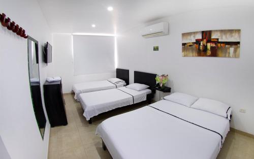 een witte kamer met 2 bedden en een bank bij Hotel Embajador del Llano in Villavicencio