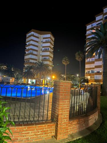 阿爾加羅沃科斯塔的住宿－Bonito Apartamento en Algarrobo-Costa，栅栏前有蓝色灯光的建筑