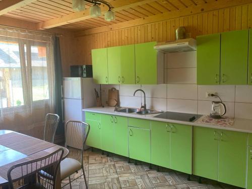 a kitchen with green cabinets and a table and a dining room at Садиба у Коржуків in Rivnya