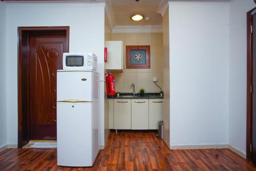 a kitchen with a refrigerator with a microwave on top at La Villa Suites Hotel in Doha
