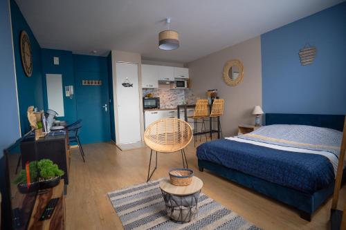 um quarto com paredes azuis, uma cama e uma cozinha em L'Effet-Mer - Tout équipé - Parking Privé - Wifi em Saint-Nazaire