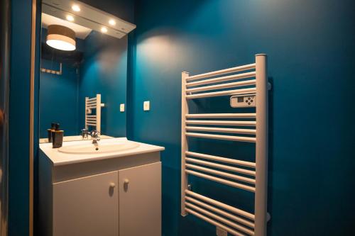 uma casa de banho com um lavatório e uma parede azul em L'Effet-Mer - Tout équipé - Parking Privé - Wifi em Saint-Nazaire