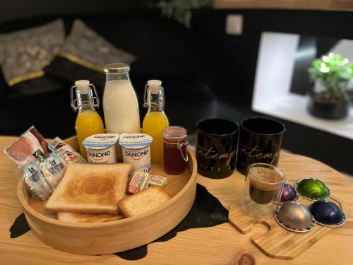 a wooden tray with toast and bottles of juice and drinks at La Pause Cosy in Champagne-sur-Oise