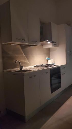 cocina con armarios blancos, fregadero y fogones en B&B Lido Apartament 10B, en Civitanova Marche