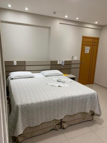 a bedroom with a large bed with a white blanket at Prudentópolis Palace Hotel in Prudentópolis