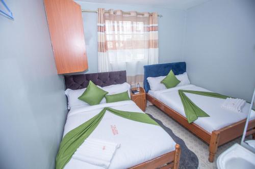 two beds in a small room with green pillows at Heritage Villa Hotel & Accomodation in Kericho