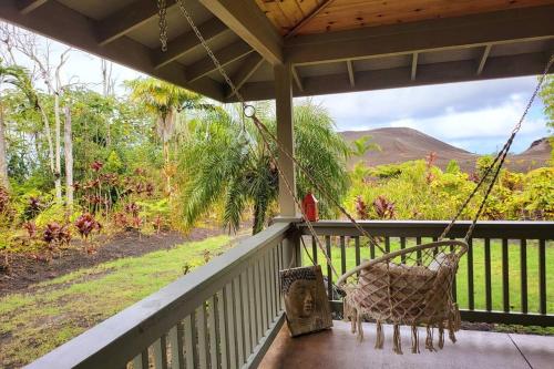 a porch with a swing and a view of a mountain at Unique Lava House by steaming crater in Pahoa