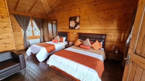 2 camas en una habitación con paredes de madera en Hotel Cabañas y Mirador Secret Garden CR, en Cartago