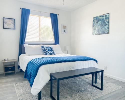 a bedroom with a bed with a blue blanket and a window at Trendy Ivy 2-bedroom Apartment Near Dt Coalinga in Coalinga