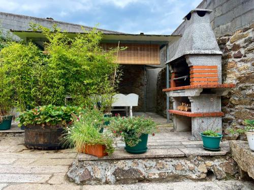 un jardín con un horno de piedra con plantas en ollas en A Casa do Abuelo, en Ourense