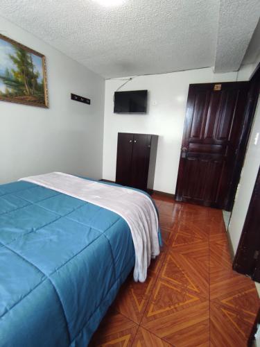 um quarto com uma cama com um cobertor azul em Hostal Buenaventura Ibarra em Ibarra