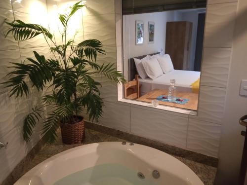 a bathroom with a bath tub and a palm tree at Vila Verde Suites in Florianópolis
