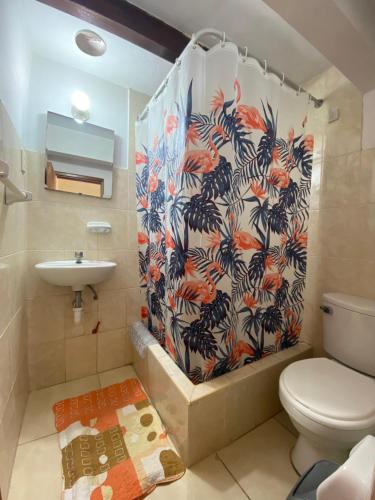 a bathroom with a shower curtain with a toilet and a sink at La Chocita Ward in Lima