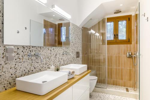 uma casa de banho com um lavatório branco e um chuveiro em The Sea House Skiathos em Skiathos Town