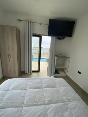 um quarto com uma cama grande e uma televisão na parede em Riviera Vichayito em Vichayito
