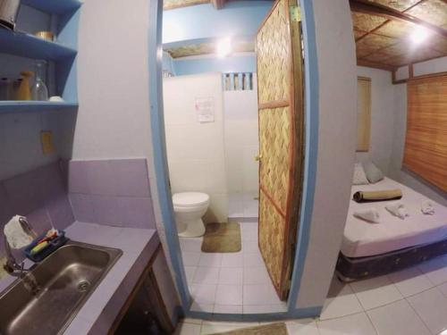 a bathroom with a shower and a toilet and a sink at Al Hamra Jungle Resort in Puerto Princesa City