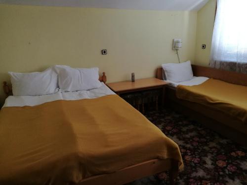 a room with two beds and a table and a window at Самостоятелни стаи в къща за гости Балкан in Ribarica