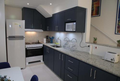 a kitchen with black cabinets and a white refrigerator at Elegante Duplex Oceanico da Elena Super Cozinha USP y UfSCAR in São Carlos