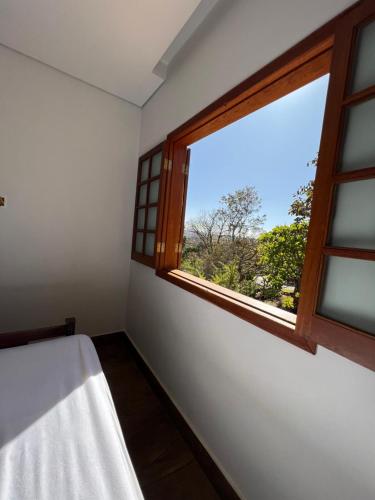 1 dormitorio con ventana y vistas a un árbol en Casa da Vista - LAGOA SANTA en Lagoa Santa