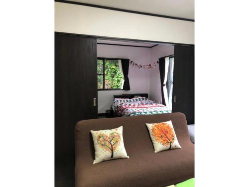 um quarto com uma cama e um sofá com duas almofadas em Fukugi no Yado - Vacation STAY 94994v em Amami