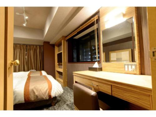 a bedroom with a bed and a desk with a mirror at HOTEL RELIEF Namba Daikokuchou - Vacation STAY 33958v in Osaka