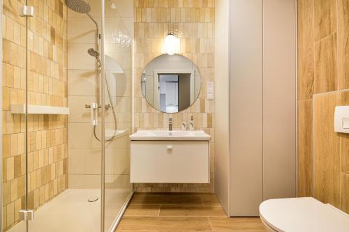 a bathroom with a shower and a sink and a mirror at Klif Apartamenty Polanki Aqua in Kołobrzeg