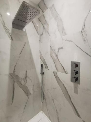 La salle de bains est pourvue d'une douche et d'un mur en marbre. dans l'établissement L'escapade, à 5 minutes de l'A6, à Dracé