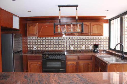 a kitchen with wooden cabinets and a black stove at Casa Luna Coyoacan in Mexico City