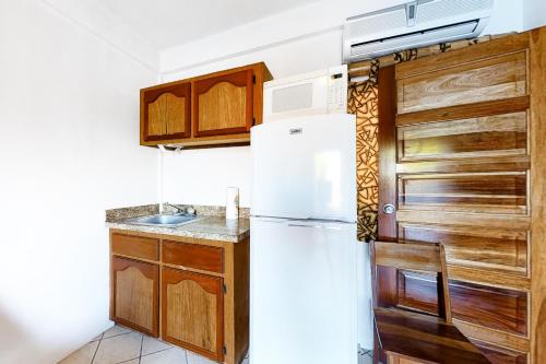 a kitchen with a white refrigerator and wooden cabinets at Mayan Falls Gold Standard and Corridor Certified in Caye Caulker
