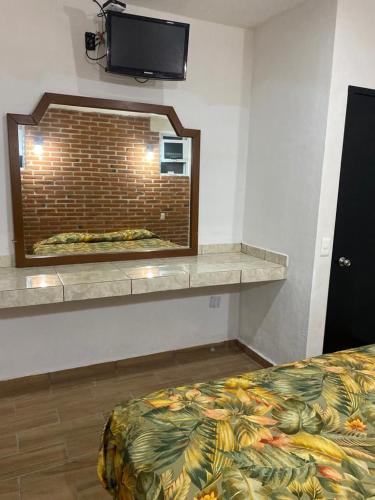 a room with a bed and a tv on a wall at Hotel Villas La Mexicana in Tecozautla