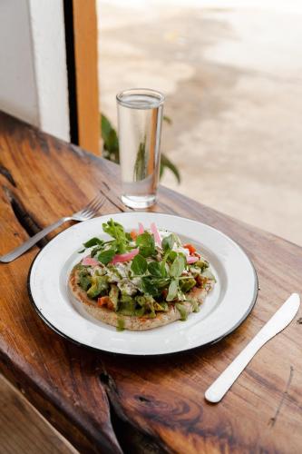 a plate of pizza on a table with a glass at Hotel San Martin La Punta in Puerto Escondido