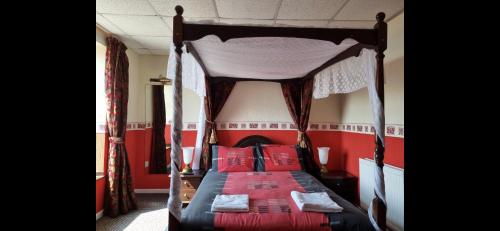 a bedroom with a canopy bed with red walls at Funky Towers in Blackpool