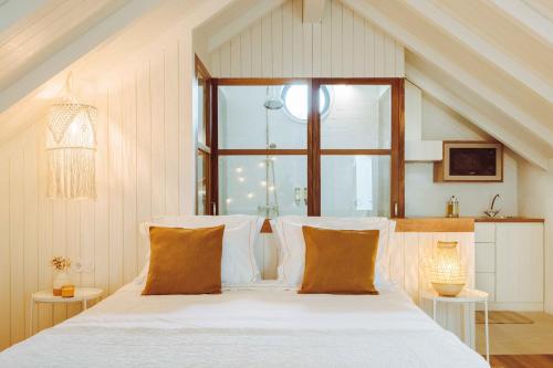 um quarto com uma cama com lençóis brancos e uma janela em Oliveiras Village — Agroturismo em Amarante