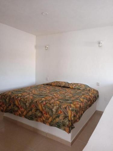 a bed in a white room with a blanket on it at Hotel Villas La Mexicana in Tecozautla