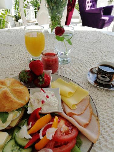 a plate of food with a sandwich and a glass of orange juice at Hotel u Liska in Kutno
