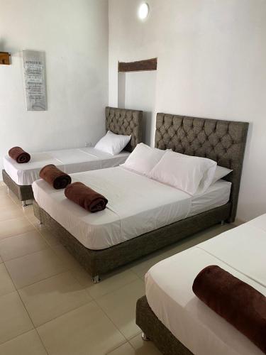 two beds in a bedroom with white walls at HOTEL PLAZA BOLIVAR MOMPOX ubicado en el centro histórico con parqueadero interno in Mompos