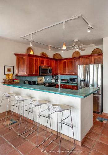 Una cocina con gabinetes de madera y un mostrador con taburetes. en Casa de Colores, Vieques, en Vieques
