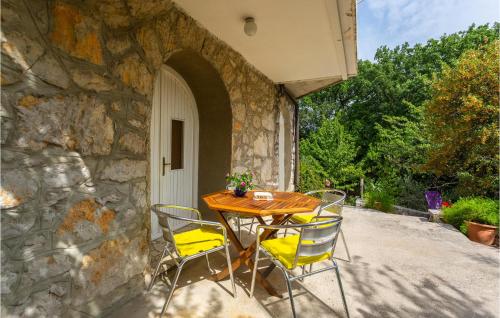 einen Holztisch und Stühle auf einer Terrasse in der Unterkunft Awesome Apartment In Omisalj With Wifi in Omišalj