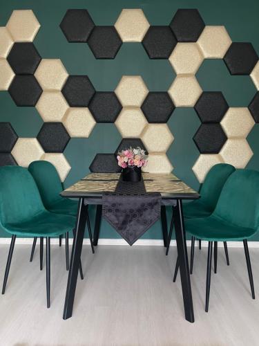 a dining room with a table and green chairs at Bella Apartman Debrecen in Debrecen