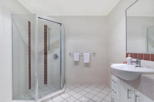 a white bathroom with a shower and a sink at La Vida on Anzac in Redcliffe